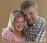 a man and woman hugging in front of a brown background